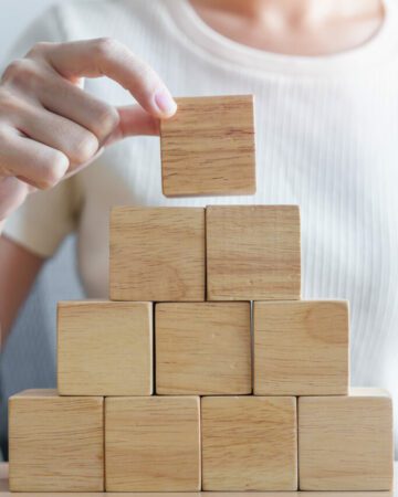 Woman hand placing wood block on the building. Leadership, Busin